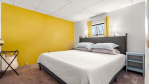 A bedroom with a bed, a nightstand, a lamp, and a window with curtains. - Nothing Fancy Older Apt~Walk to Downtown~ King Bed (Dover)