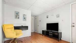 A room with a yellow chair, a black entertainment unit, and a flat-screen TV. - Nothing Fancy Older Apt~Walk to Downtown~ King Bed (Dover)