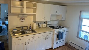 A kitchen with white cabinets, a gas stove, and a sink.