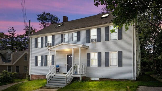 A two-story house with a front porch, a small front yard, and a driveway.