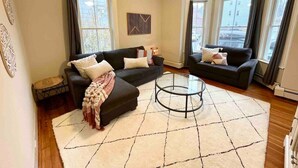 A living room with two dark sofas, a coffee table, and a patterned rug. - 2 BR City Sanctuary - 5 Mins to Historical Salem! (Beverly)