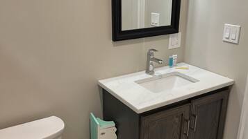 Une salle de bain avec des toilettes, un lavabo et un miroir.
