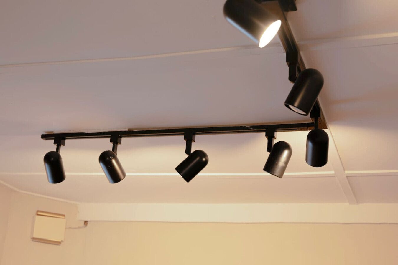 A ceiling-mounted track lighting system with five spotlights.