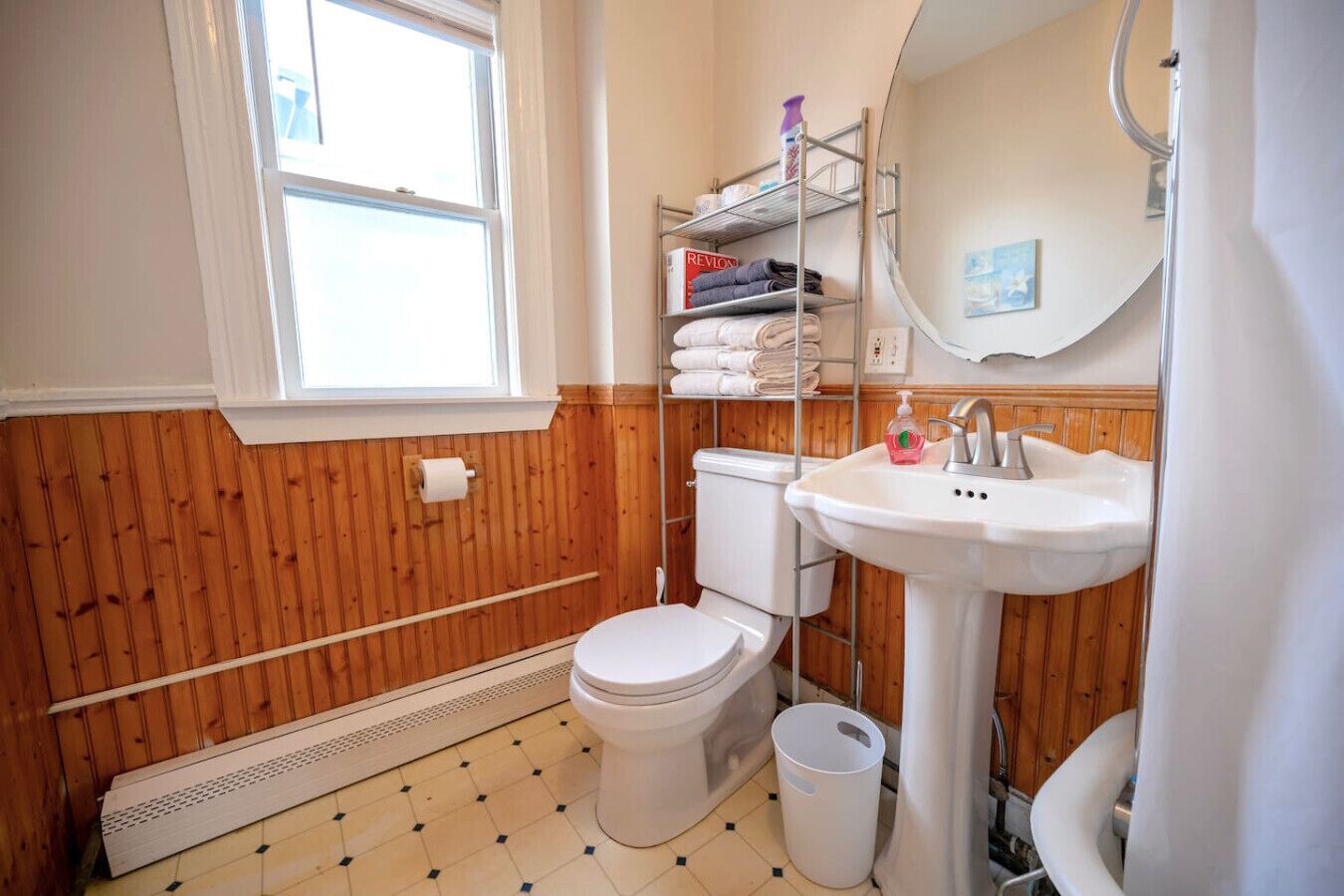 A bathroom with a toilet, sink, and wooden paneling.
