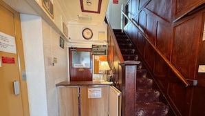 Un comptoir d’accueil avec une pancarte indiquant les heures d’enregistrement et une plaque « chambre privée » au-dessus de la porte.