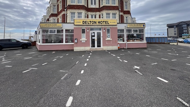 Un hôtel DELTON à deux étages, avec une enseigne indiquant que toutes les chambres, les étages et les espaces de divertissement sont accessibles par ascenseur.