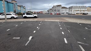 Une rue bordée de voitures garées, avec des immeubles et un passage piéton.