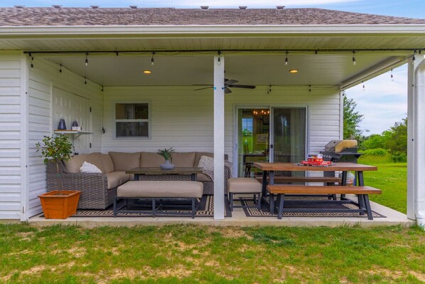 Une terrasse couverte avec un canapé, une table et un barbecue.
