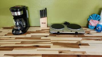 A kitchen counter with a coffee maker, knife block, electric griddle, and cleaning supplies.
