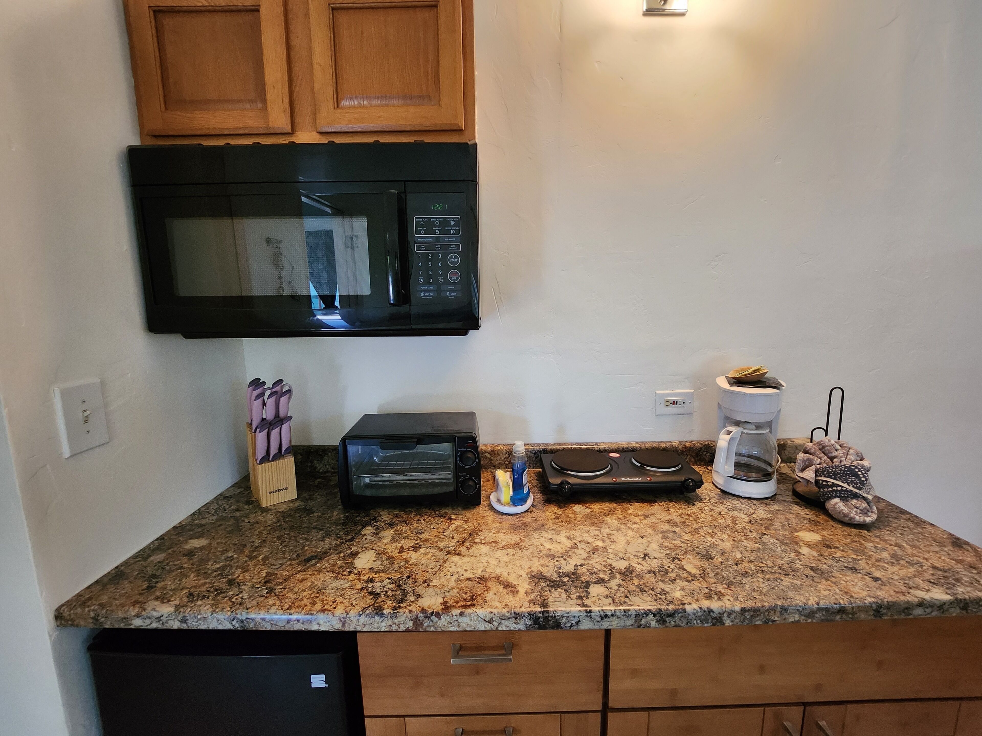 A kitchen with a microwave, toaster, coffee maker, and a dish rack.