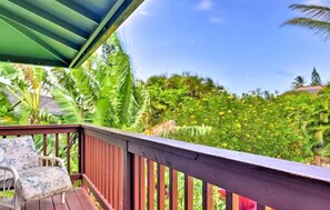 A wooden deck with a chair, surrounded by lush tropical vegetation and a clear blue sky. - Yonegan Maui Getaways - Haiku  (Haiku)