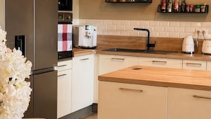 Una cocina moderna con refrigerador, cafetera y encimera de madera.