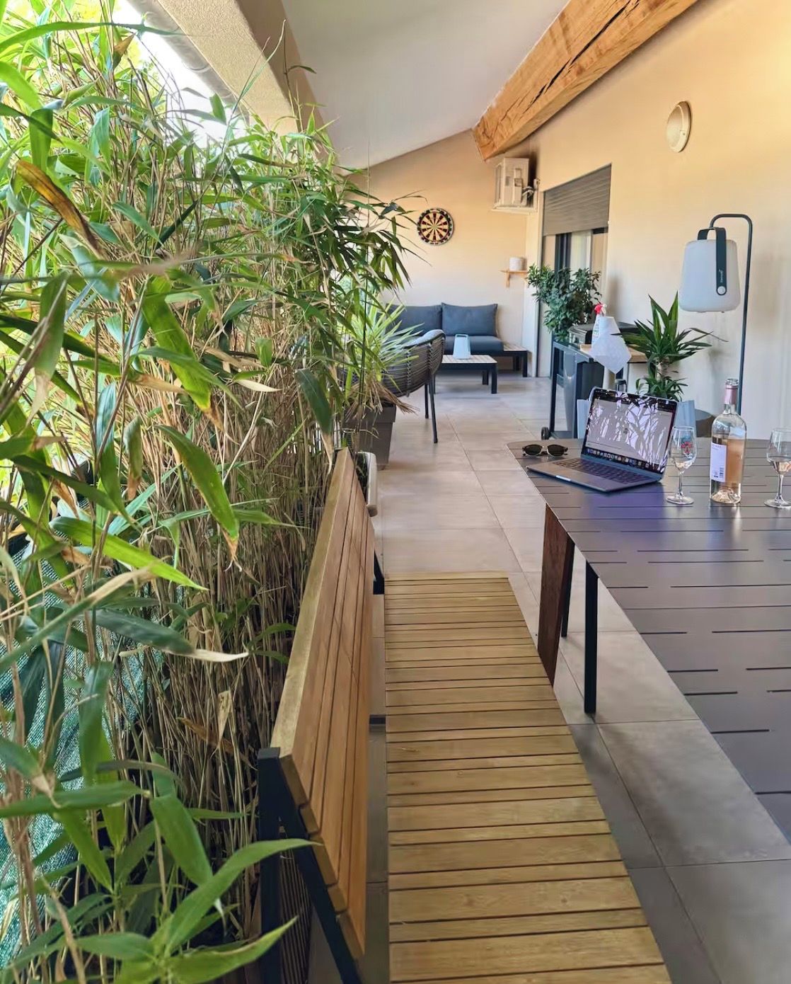 Ein modernes Interieur mit einer Holzbänkl, einem Esstisch mit Weingläsern und einem Laptop.