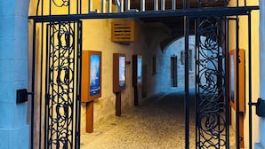 Una entrada arqueada a un cine con puertas de metal negro ornamentadas y un cartel que dice 