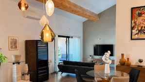 Una cocina moderna con encimera de madera, luces colgantes y una zona de comedor con mesa redonda y sillas.