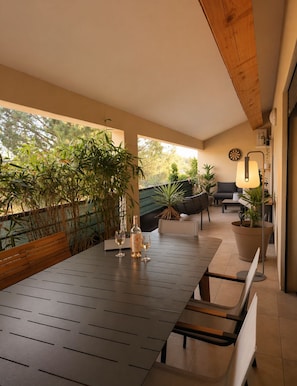 An outdoor dining area with a long table, chairs, and potted plants. - Large apartment, 103 m² • 2 suites • Patio • 2 private parking spaces (L'Isle-sur-la-Sorgue)