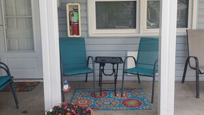 Een veranda met twee stoelen, een klein tafeltje en een bloempot.