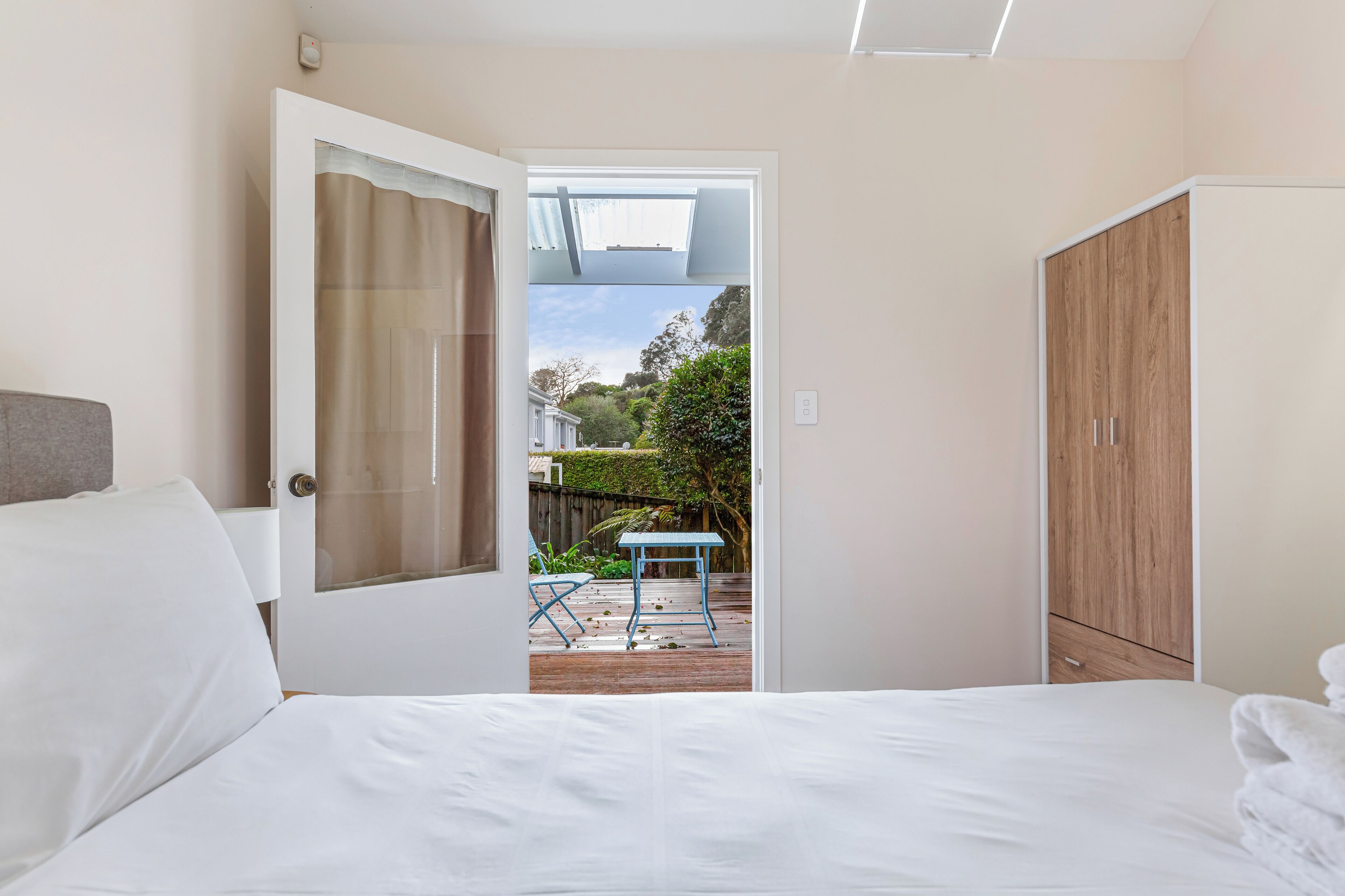 Une chambre à coucher comprenant un lit, une armoire et une porte donnant sur une terrasse extérieure avec une table et des chaises.