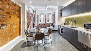 Een moderne keuken met een bakstenen muur, een eethoek met stoelen en een trap naar een hoger niveau.