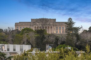 A large, historic building with a symmetrical facade, surrounded by dense foliage and modern structures. - Modern 2BR Penthouse for Families by Zodiak Stays (Auckland)