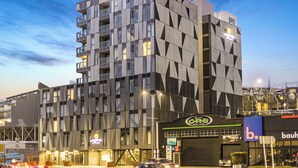 A modern building with a geometric facade, a visible sign for 'C. B. S.' and 'b. bauhaus', and a street with cars. - Modern 2BR Penthouse for Families by Zodiak Stays (Auckland)