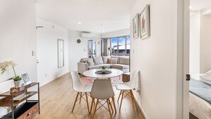 A modern living room with a sofa set, a coffee table, and a dining area with chairs.