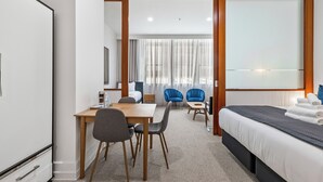 Ein Hotelzimmer mit einem Bett, einem Schreibtisch, zwei Stühlen, einem kleinen Tisch und einem Fernseher.