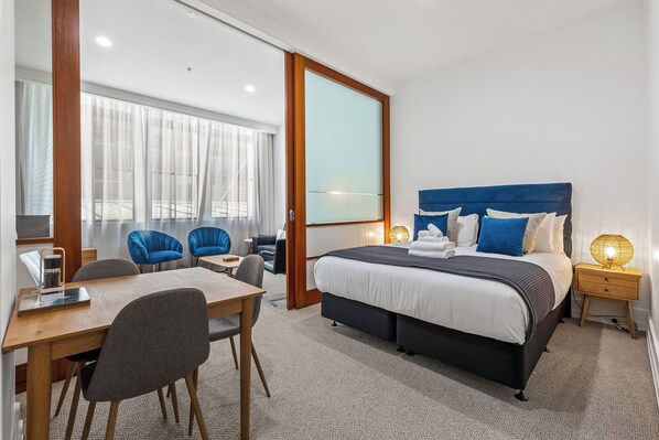 Ein modernes Hotelzimmer mit einem großen Bett, einem Schreibtisch und zwei blauen Sesseln.