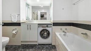 Ein modernes Badezimmer mit Waschmaschine, Toilette und Badewanne.