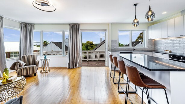 A modern kitchen with a large island, bar stools, and pendant lighting. - Serene 2BR Home in Meadowbank by Zodiak Stays (Auckland)