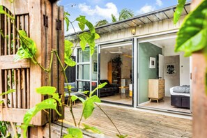 Uma casa moderna com grandes portas de vidro que dão para uma sala de estar com sofá, um armário de madeira e ventilador de teto.