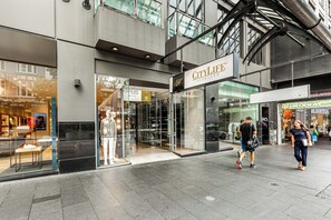 A modern building with a glass facade, a sign reading "CityLife Auckland," and a pedestrian walkway. - City Getaway 1BR Apt w Pool & Gym I Zodiak Stays (Auckland)
