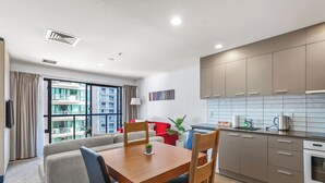 A modern apartment with a dining area, kitchen, and a balcony with a city view.