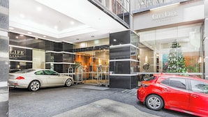 A hotel entrance with two cars parked in front, a Christmas tree, and a sign for CityLife Auckland.