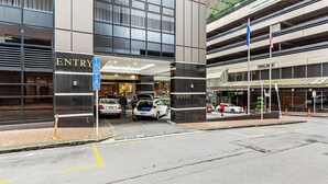 A modern building with an 'ENTRY' sign, a parking area, and a multi-level parking structure.
