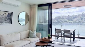En moderne stue med sofa, sofabord og udsigt til en balkon med udendørs møbler.