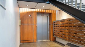 An elevator with a wooden panel design and a mailbox wall with numbered slots.