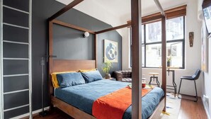 A modern bedroom with a four-poster bed, a desk, and a chair.