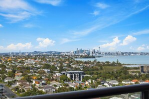 A cityscape with residential buildings, a waterfront, and a prominent skyline including tall buildings and a tower.