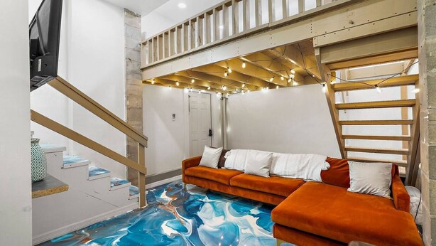 Un intérieur moderne avec un escalier en bois, un canapé et un plafond décoré de guirlandes lumineuses.