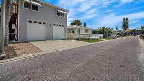 Une rue résidentielle bordée de maisons à deux étages, dont certaines sont dotées d’un garage, d’une allée et d’un petit jardin devant, délimité par une clôture.