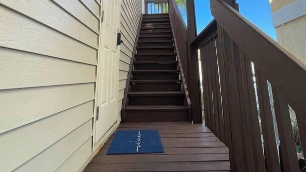 Una escalera de madera que lleva a un espacio cubierto con un tapete azul al final.