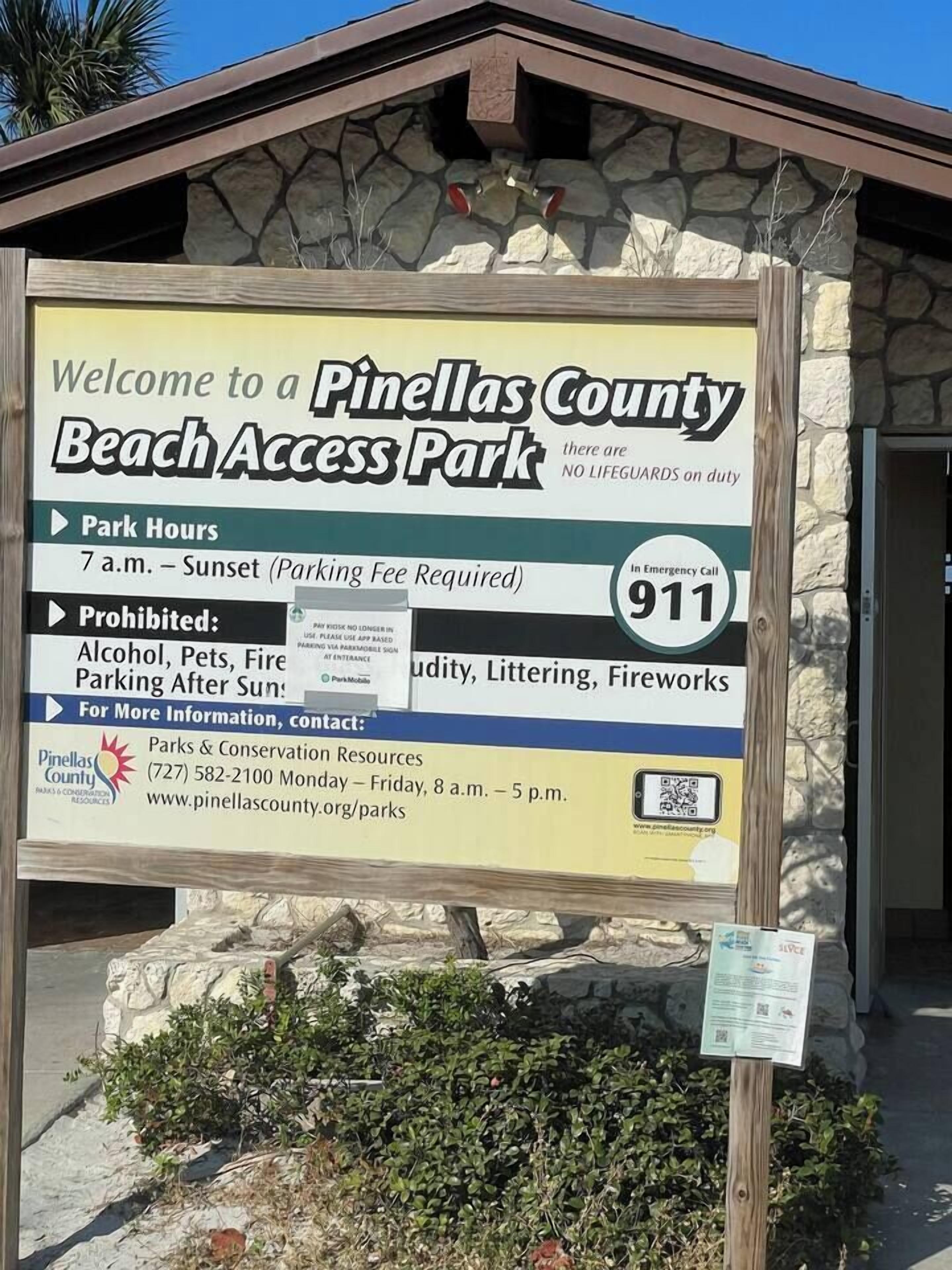 A sign for Pinellas County Beach Access Park with park hours, prohibited activities, and emergency contact information.