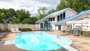 A swimming pool with a diving board, lounge chairs, and a covered patio area. - The South East Guest Suite is the soulful, art-filled heart of the House of Joy. (Preston)