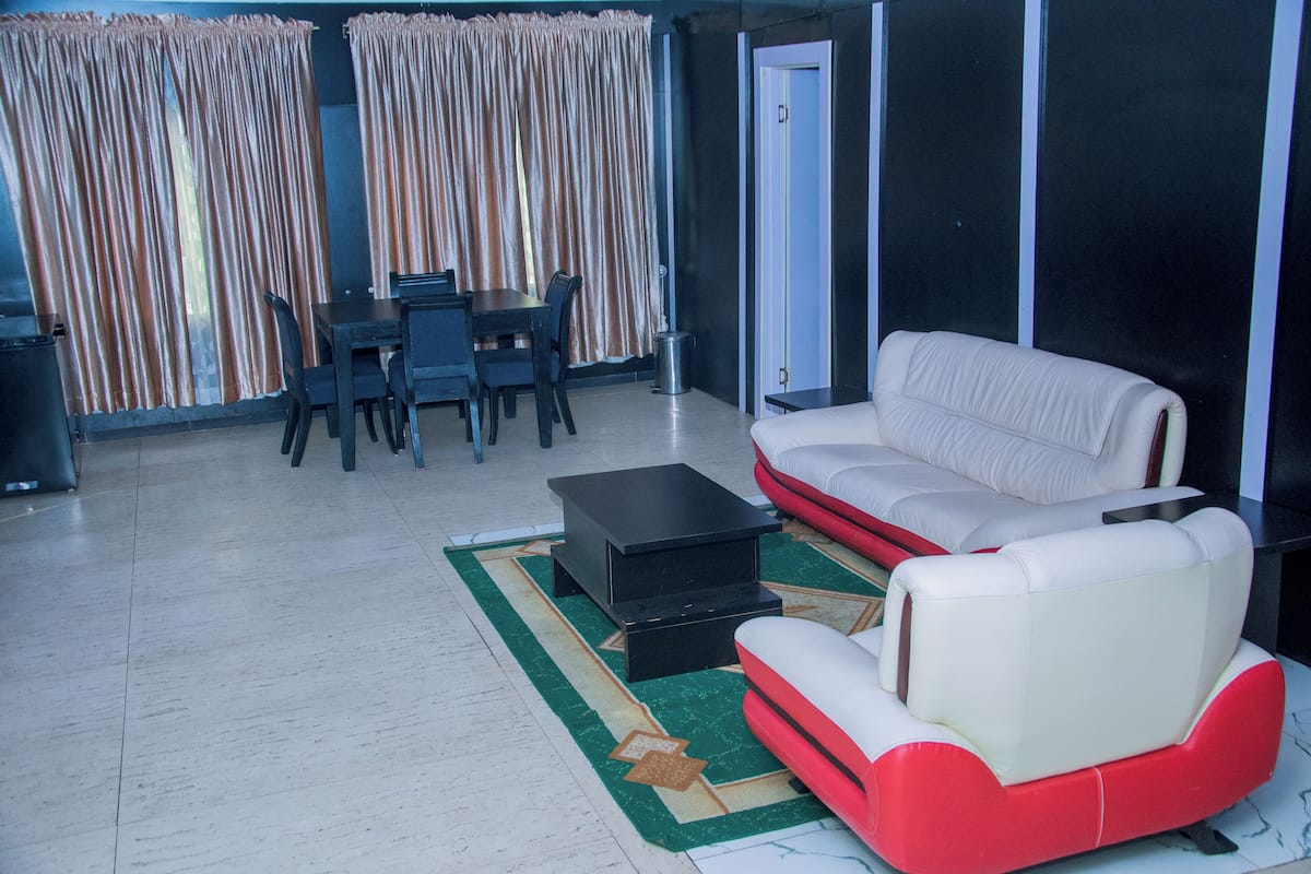 A living room with a sofa, a coffee table, a dining table with chairs, and curtains.