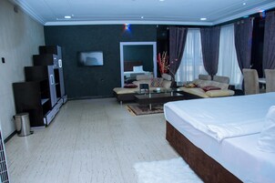 Una habitación de hotel moderna con una cama grande, un sofá, una mesa de centro y un televisor.
