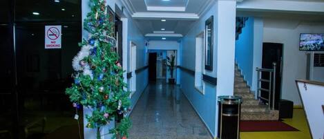 A hallway with a Christmas tree, a no smoking sign, and a staircase.
