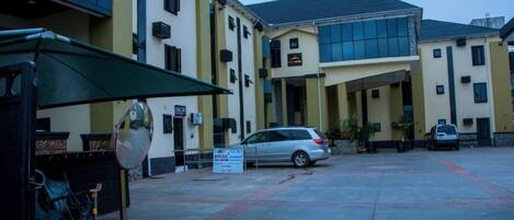 Un edificio con estacionamiento, un letrero que dice 'KETT ACEY' y un coche estacionado al frente.