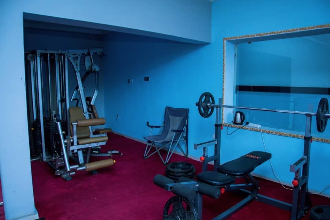 A gym with weightlifting equipment, a bench, and a folding chair.
