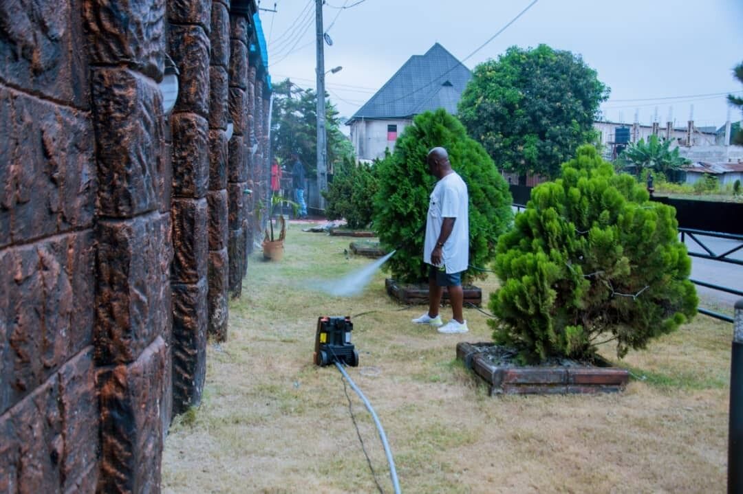A man using a pressure washer on a brick wall.